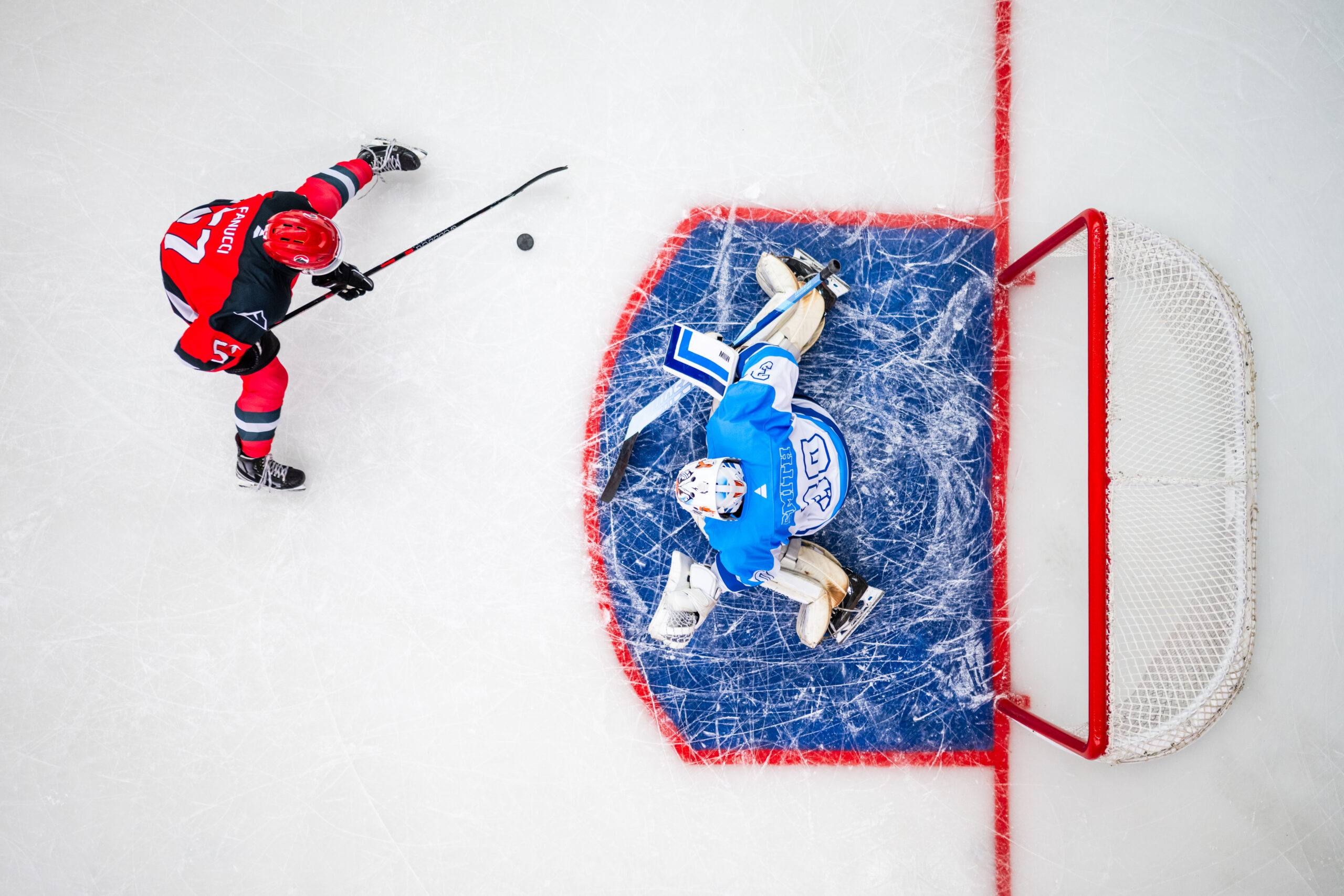 Overhead view of hockey player and goalie square up on the ice.
